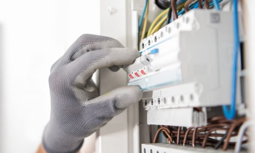 Electrician Wearing Safety Gloves Testing Fuses Inside an Apartment Located Electric Box.