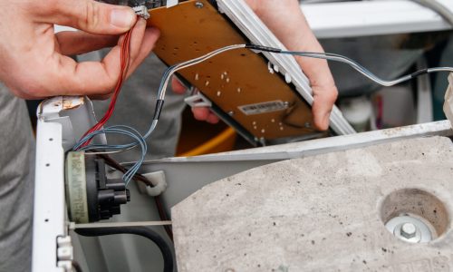 Handyman repairing a washing machine. The hands of a man disassemble the washing machine. Repair and dismantling of the washing machine. Close-up